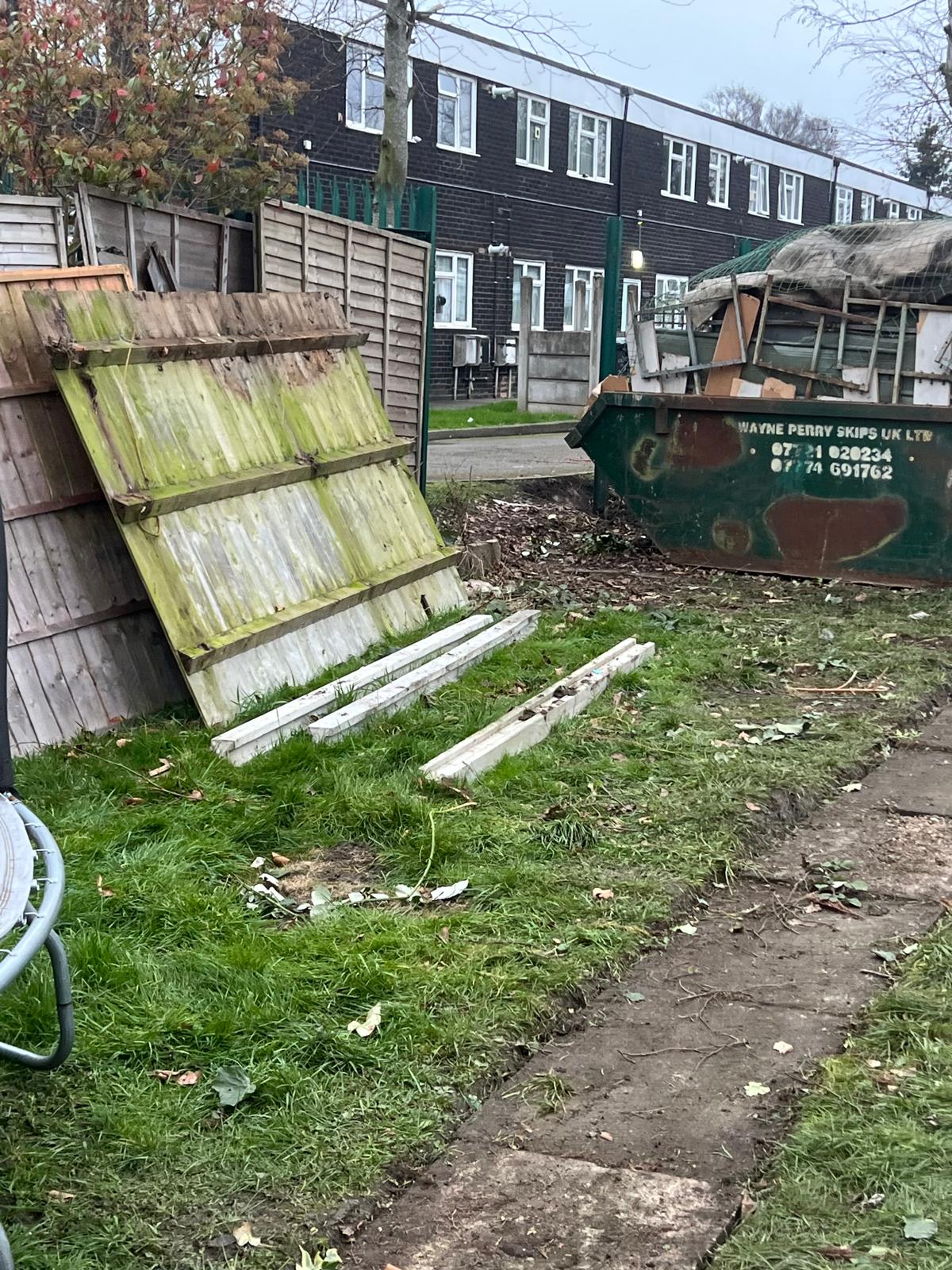 Old fence panels removed ready for replacement with skip on site
