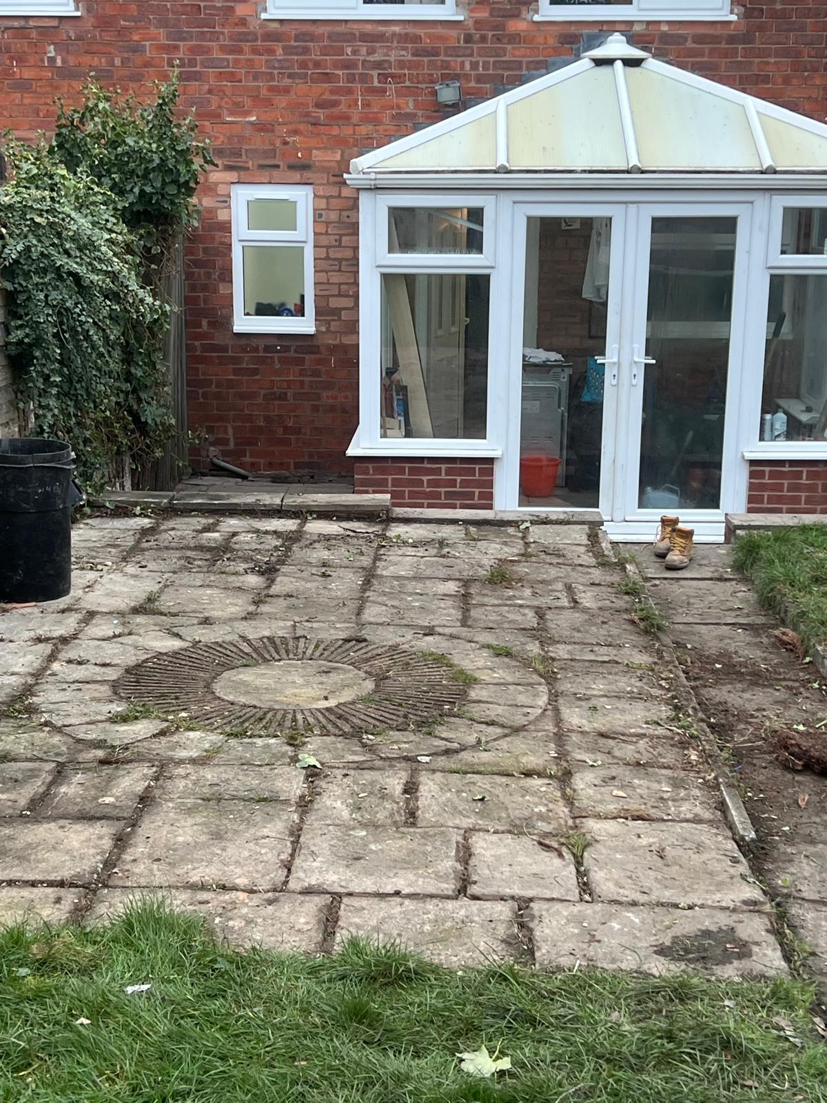 Patio area before repair with old paving slabs and conservatory