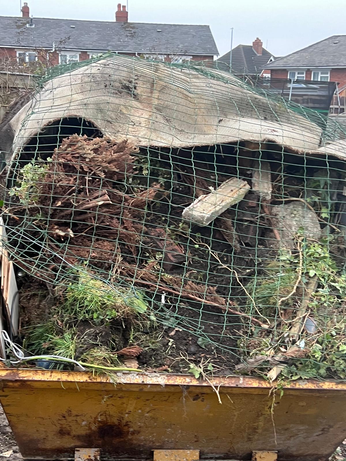Large skip overflowing with garden debris after full garden clearance