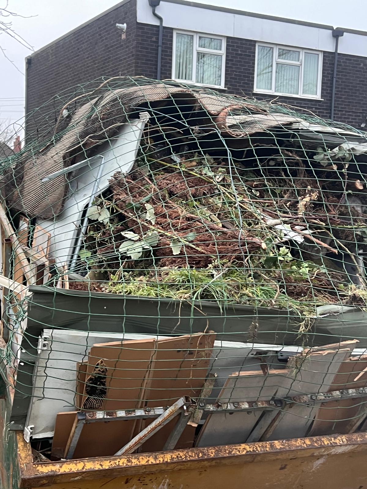 Skip filled with garden waste and branches from garden clearance